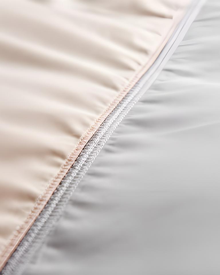 Close view of precise stitching along a pale duvet cover on a made bed