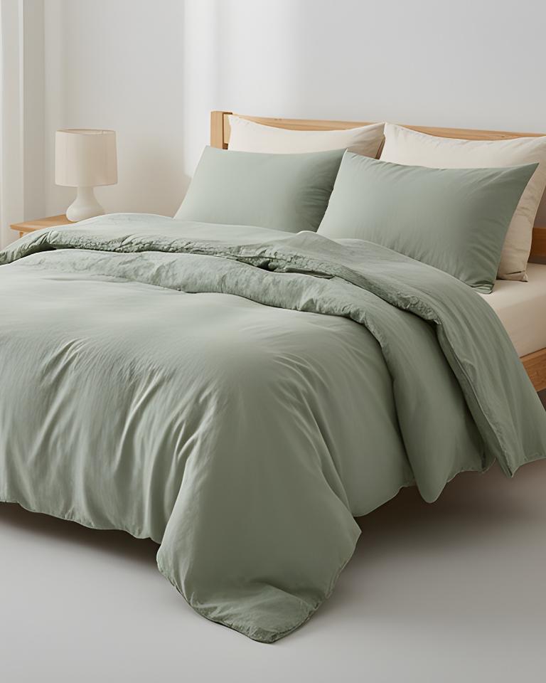 Light bamboo duvet set layered in sage green on a simple wooden bed