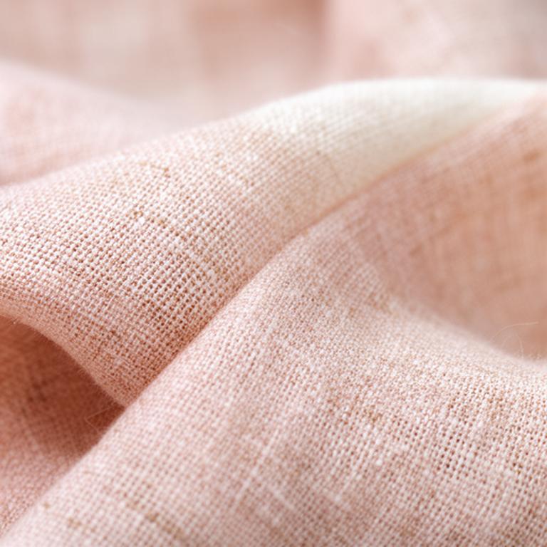 Natural linen fabric showing a fine woven texture in soft blush and cream tones